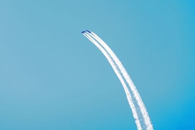 Low angle view of airplane flying against clear blue sky