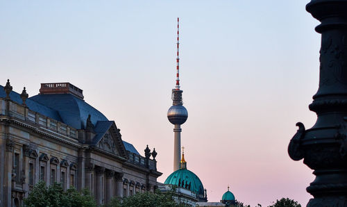 Communications tower in city against clear sky