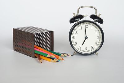 Close-up of clock on table against white background