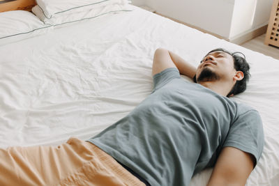 Young man sleeping on bed at home