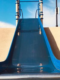 Empty seats in park against blue sky