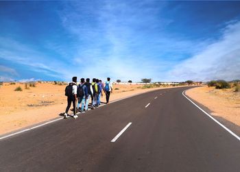 Rear view of people walking on road