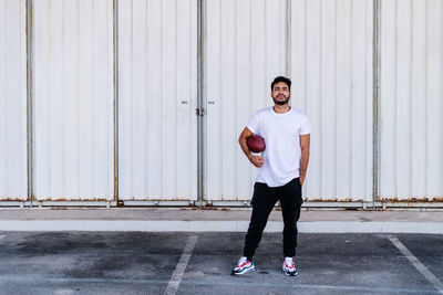 Full length portrait of young man standing against wall