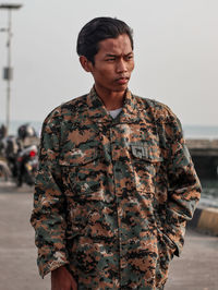 Young man looking away against sky