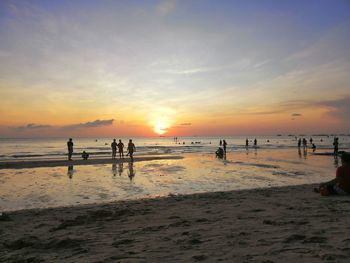 Silhouette people on beach against sky during sunset