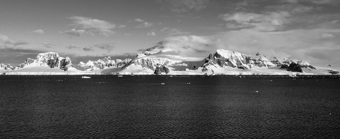 Scenic view of snowcapped mountains by sea against sky