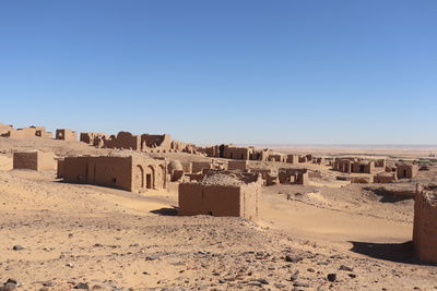 Built structure on sand against clear blue sky