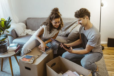 Man sharing photo frame with girlfriend while unboxing cardboard boxes at home