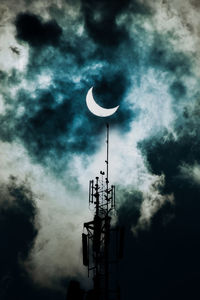 Low angle view of communications tower against cloudy sky