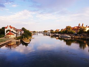 Scenic view of river by buildings in town against sky