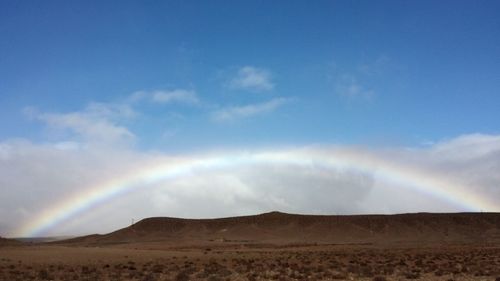 Scenic view of rainbow over landscape against sky