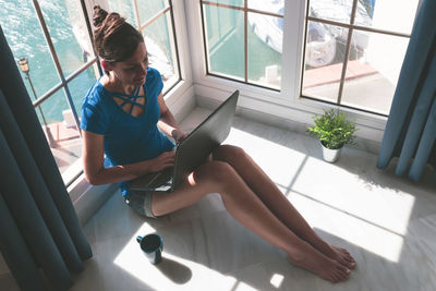 Young woman working with laptop at the window at home. freelance work at home concept.