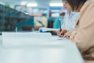 Midsection of woman using smart phone on table