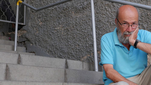 Senior man sitting on stairs against wall