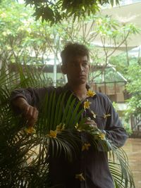 A man with frangipani flowers at the top of his corduroy shirt