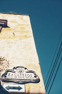 Low angle view of text on building against clear blue sky