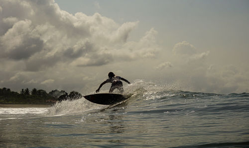 Man surfing in sea against sky