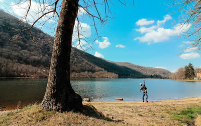 Rear view of man throwing stones into lake