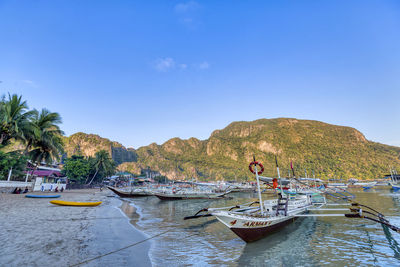 Boats moored in sea against blue sky