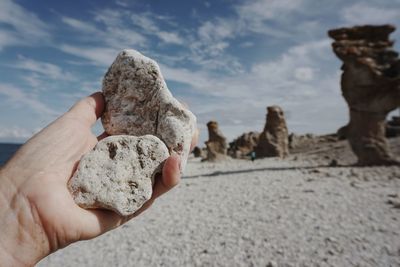 Close-up of person holding rock against sky