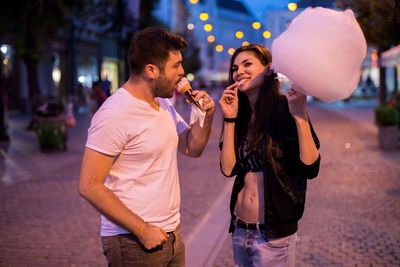 Young couple kissing on street in city at night