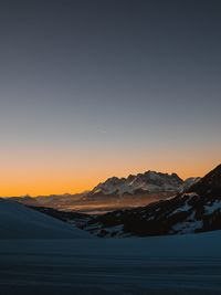 Scenic view of snowcapped mountains against clear sky during sunset