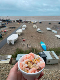 Midsection of person holding ice cream on beach