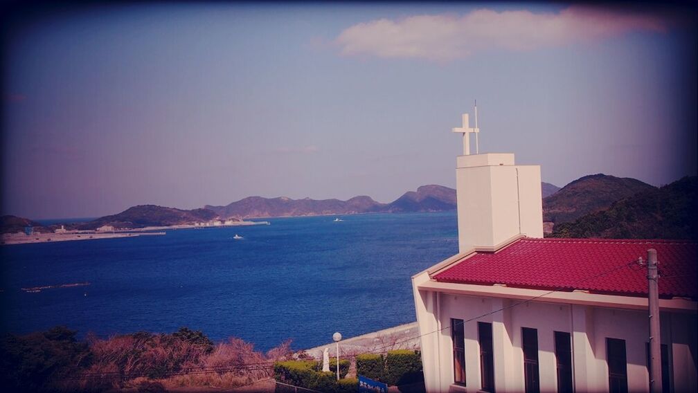 built structure, architecture, building exterior, sea, lighthouse, mountain, sky, water, scenics, transfer print, tranquility, auto post production filter, tranquil scene, tower, protection, beauty in nature, nature, guidance, horizon over water, mountain range