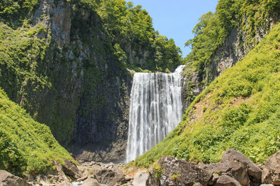 Scenic view of waterfall against rocky mountains