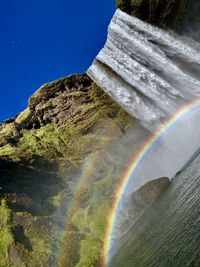 Scenic view of rainbow over mountain against sky