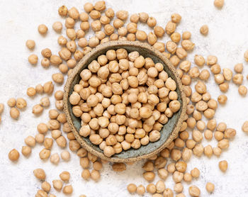 Bowl of raw dry chickpea on white table top view