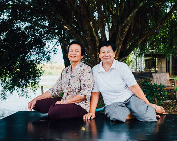 Portrait of smiling couple sitting on tree