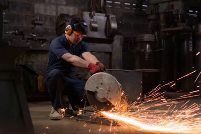 Young man welding machine at factory