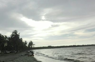 View of calm beach against cloudy sky