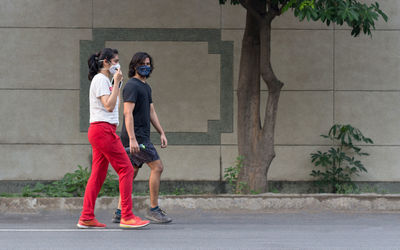 Side view of couple wearing mask walking on road