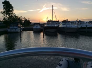 Sailboats moored at harbor during sunset