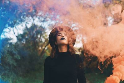 Young woman looking up while standing in park