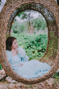 Woman wearing blue dress sitting in wooden swing