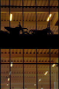 Silhouette motorcycles in illuminated orange parking garage seen from window