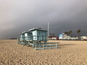 Hut on beach by sea against sky