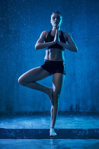 Full length portrait of woman standing against blue background