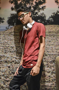 Young man looking away while standing outdoors