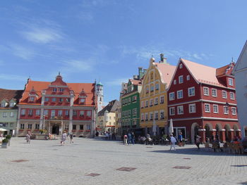 People on street amidst buildings in town against sky