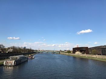 Bridge over river amidst buildings in city against sky