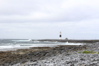 Lighthouse by sea against sky