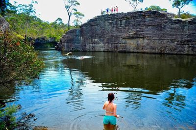 Rear view of shirtless man standing in lake