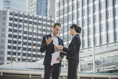 Business people discussing while standing against building