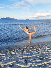 Young gymnast on beach against sky