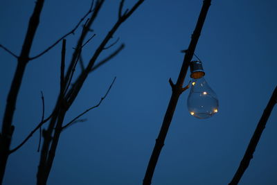 Low angle view of illuminated light bulb against blue sky