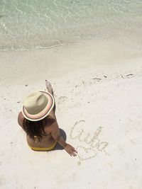 High angle view of woman sitting on sand at beach